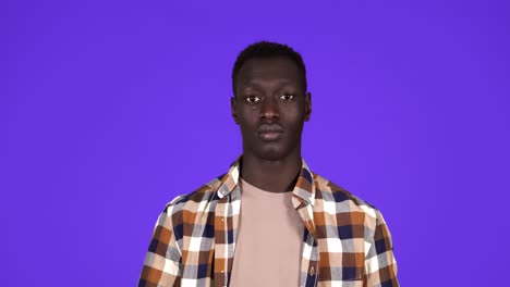 happy, smiling african american man in good mood on blue background. gesturing with thumbs up, like gesture - human emotions