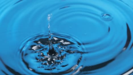 two droplet falling into blue water. zoom. two falling drops of water, causing ripples.