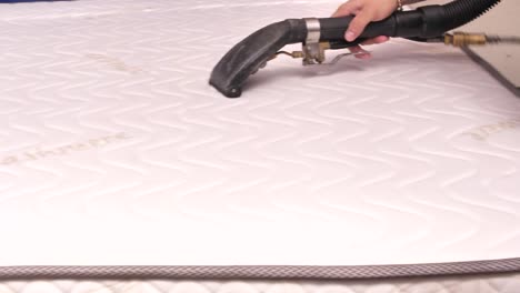 cleaning mattress with professional extraction method using vacuum cleaner, close up