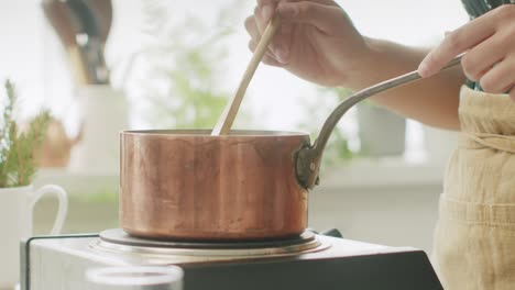 Woman-stirring-pasta-in-saucepan-on-stove