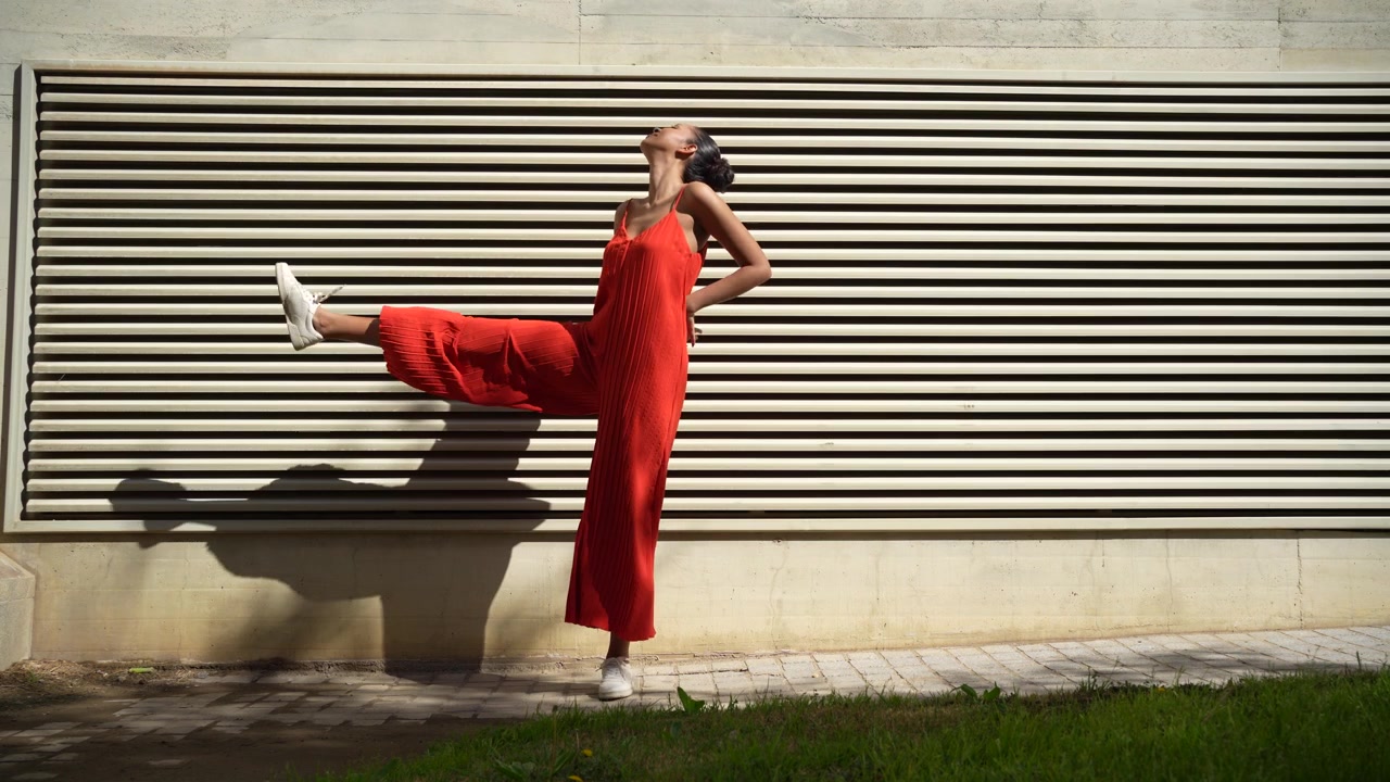 Una giovane donna elegante posa con un abito rosso brillante su uno sfondo urbano vivace