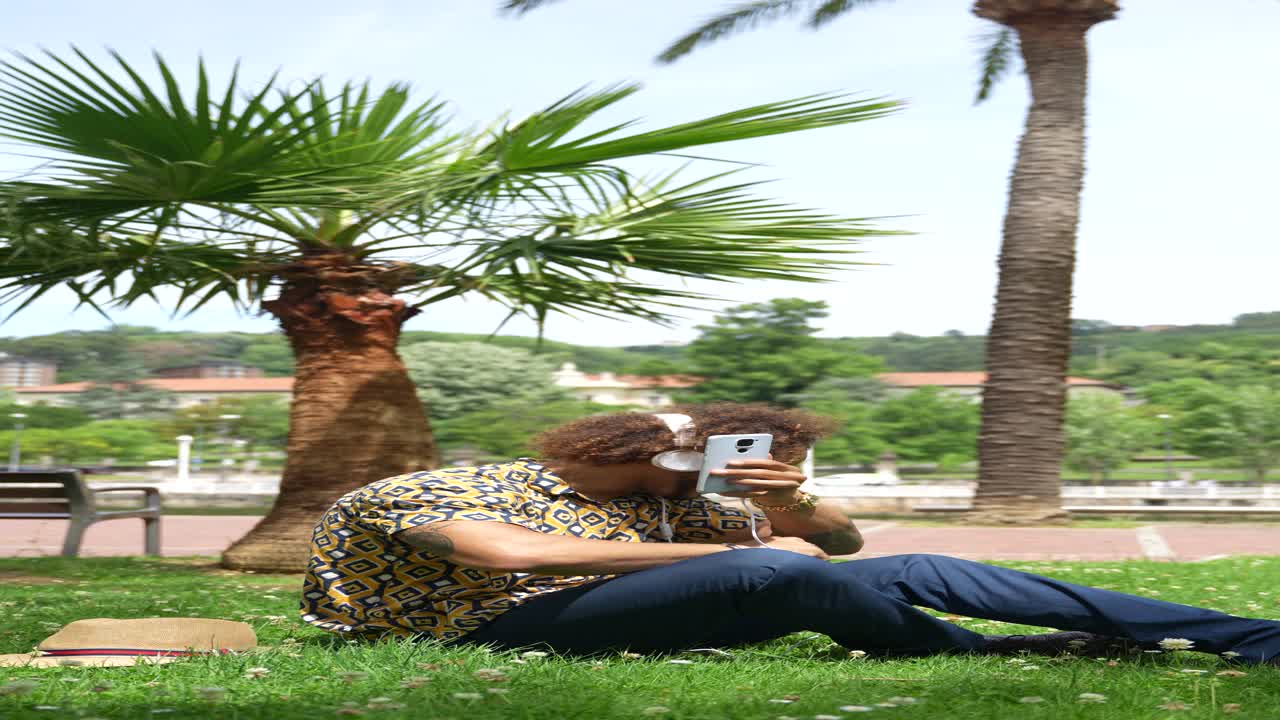 Man relaxing in park with headphones and phone