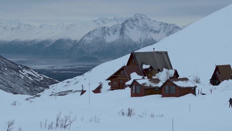 Snow-covered-Hatcher-Pass,-skier-traveling-toward-lodge,-slow-motion-4k