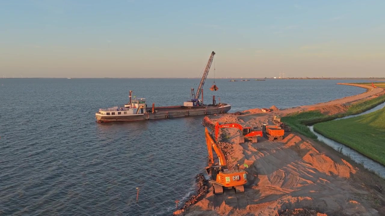 Chiatta da costruzione ed escavatore al lavoro sulla costa