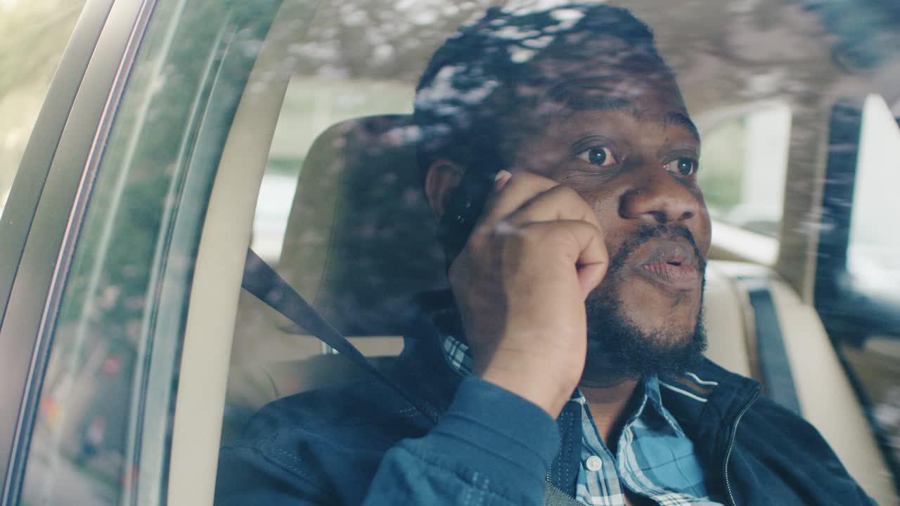 Handsome Young Entrepreneur Traveling on a Passenger Seat of a Car Makes a Phone Call, Talks with Clients or Relatives. Camera Shot from Outside the Vehicle.