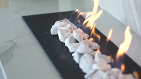 Close-up-slow-motion-tracking-shot-of-indoor-gas-fire-place-with-white-pebbles