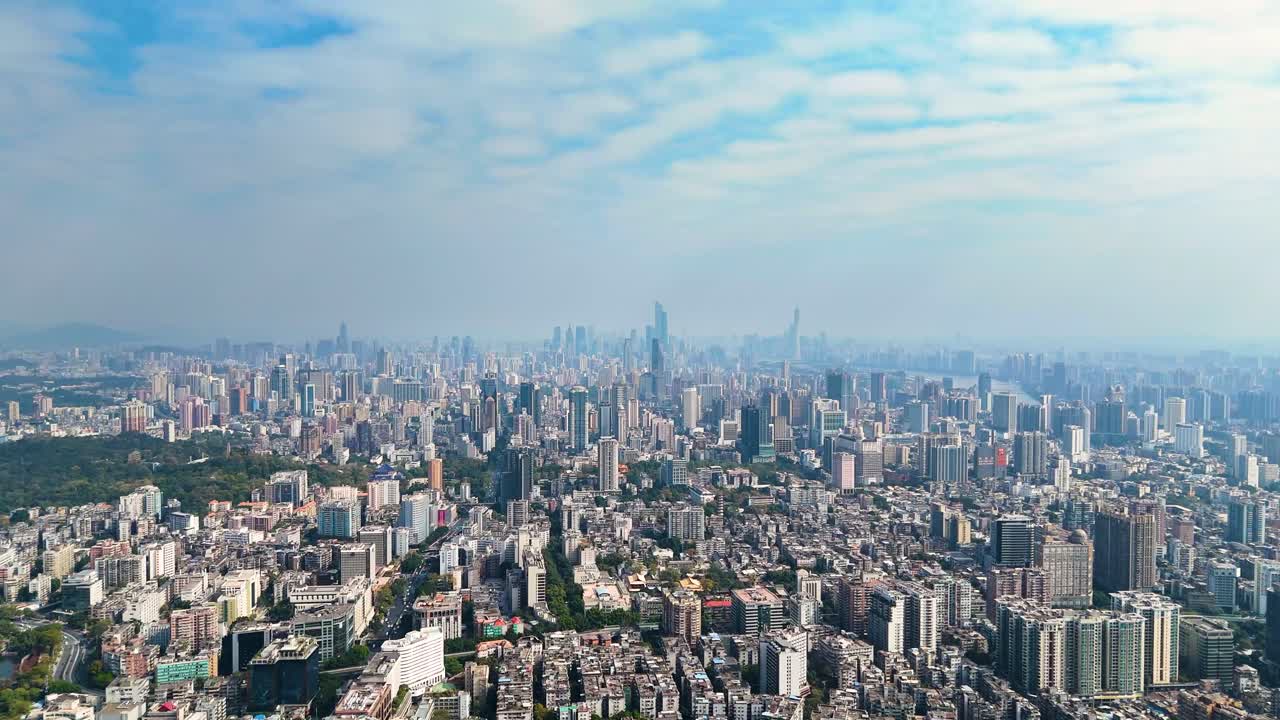 Aerial view of Guangzhou’s cityscape during the day, featuring a vast skyline with modern skyscrapers, dense urban housing, and green spaces. The scale and architecture of the metropolis in China.