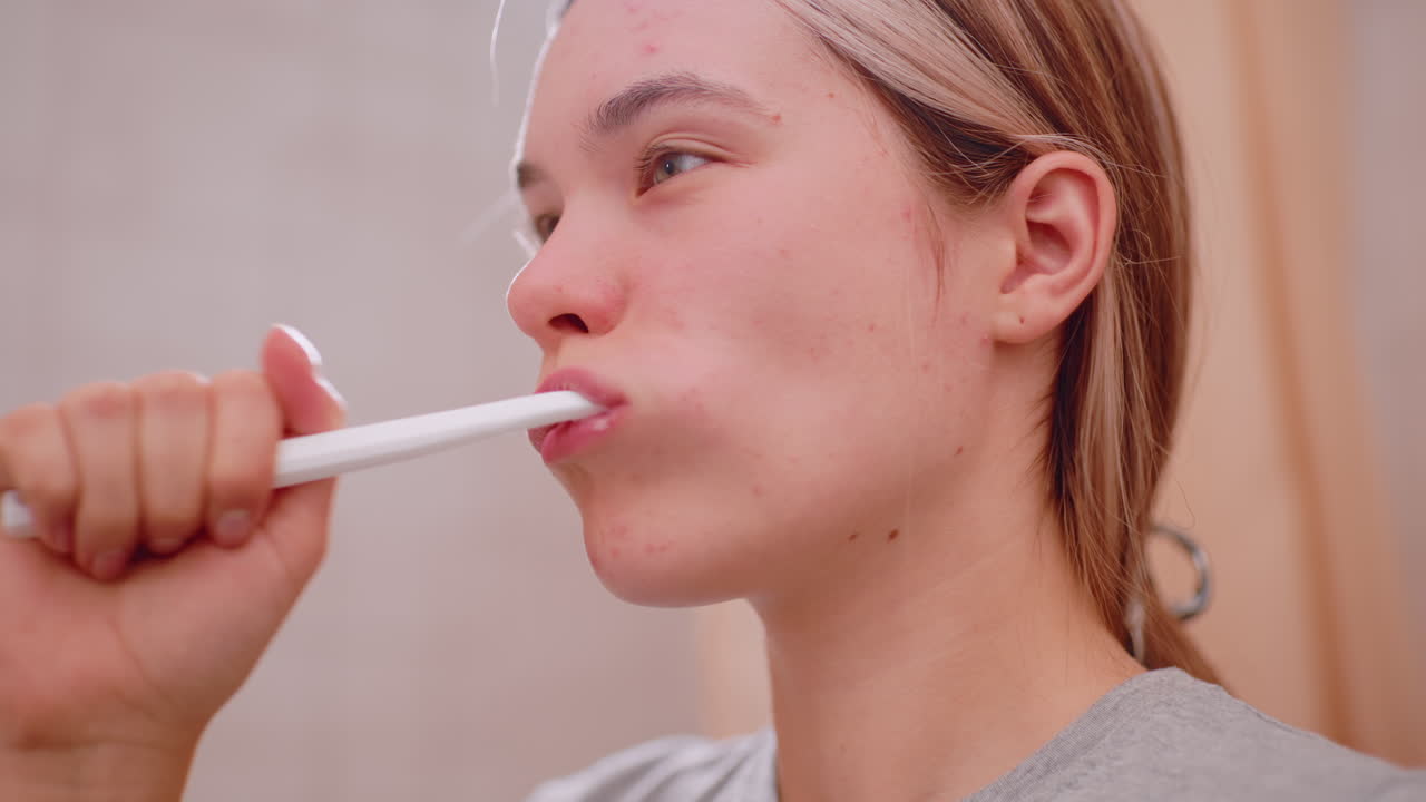 Close up side view of woman brushing teeth with toothbrush, focusing on oral hygiene, dental care, morning routine, health, wellness, and personal grooming in bathroom