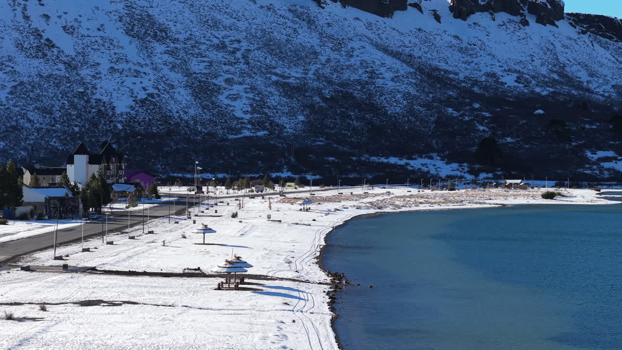 Winter landscape of Caviahue, showing frozen shorelines, water, and distant houses