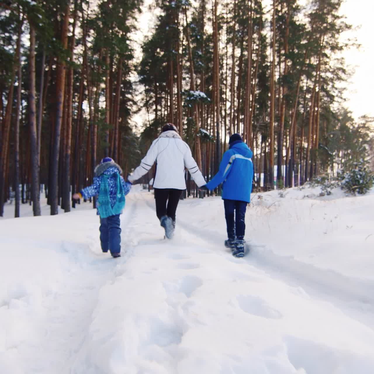 madre caminando juguetonamente con niños en la nieve 01