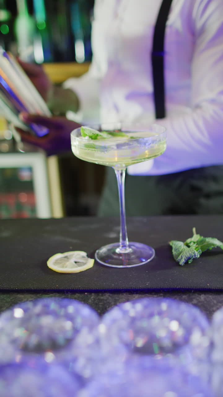 Vertical video of african american barman preparing cocktail at a bar