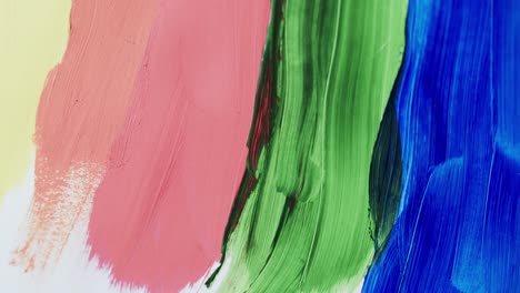 close up of multi coloured paint stripes on white background with copy space, slow motion