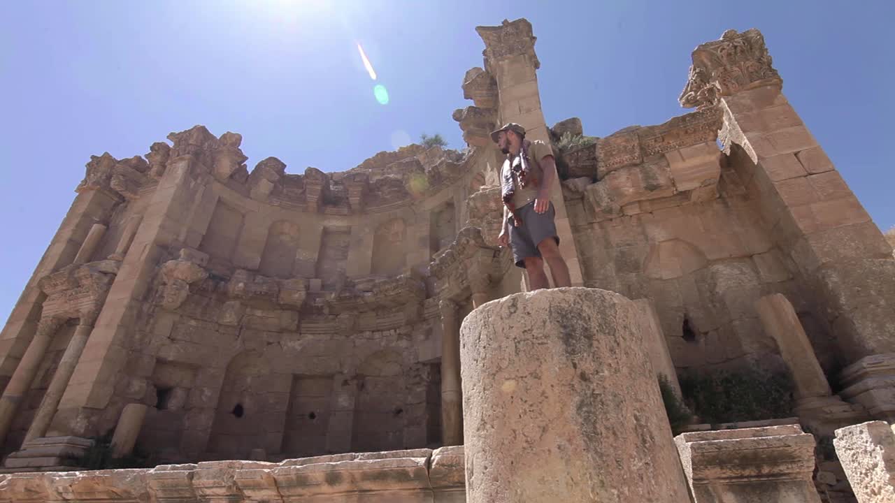 Adventurer standing in ancient pillar, sun flare, clear sky, Jerash, Jordan, low angle shot