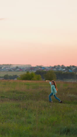 active kid runs along lush field at dusk sunlight. cheerful preschooler girl plays at farmland in warm evening. little child enjoys freedom