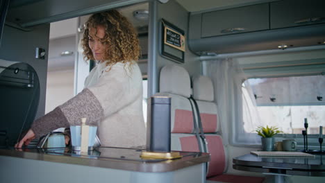 traveller cooking trailer kitchen close up. curly woman preparing coffee in van