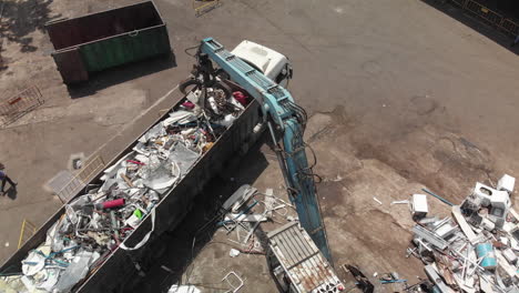 garbage crane loading a truck with debris from a junkyard