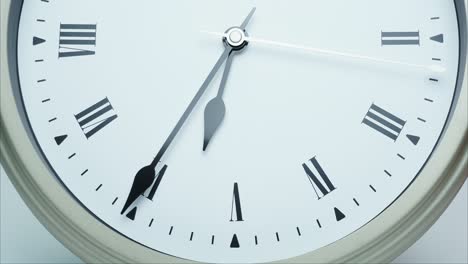 time lapse silver wall clock short hand points on roman numerals.