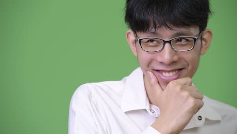 young happy asian businessman smiling while thinking