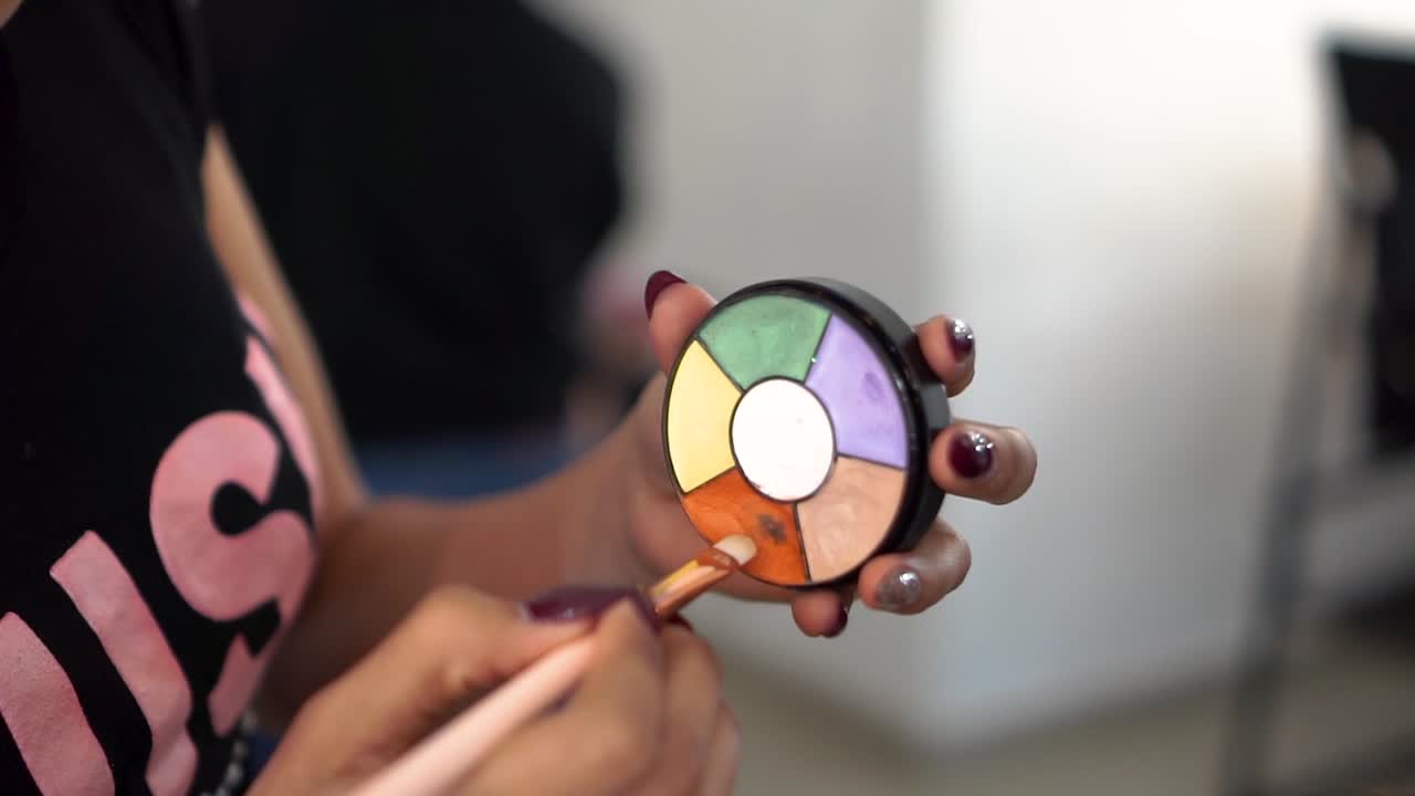 Makeup artist hands with eyeshadow kit and eye brush. Handheld