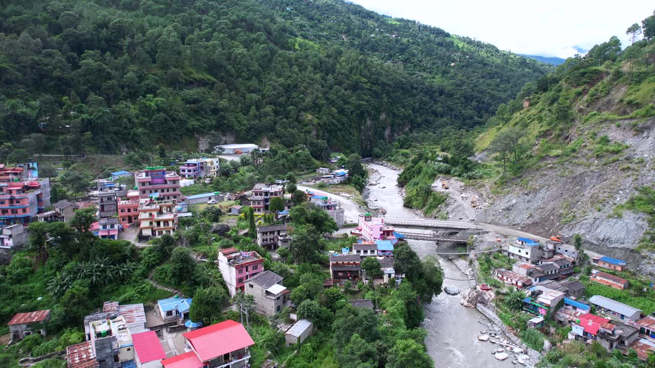 Panorama aéreo de casas de pueblo a orillas del río Gandaki con vista a la montaña, dron volando en órbita sobre Marpha en Nepal.
