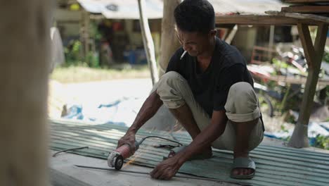 worker using angle grinder to cut metal bar outdoors
