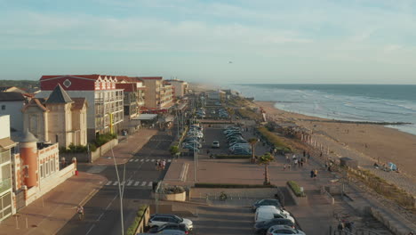 Small-Beach-Town-Village-Lacanau-Promenade-in-South-of-France-at-Sunset,-Slow-Aerial-high-angle-forward