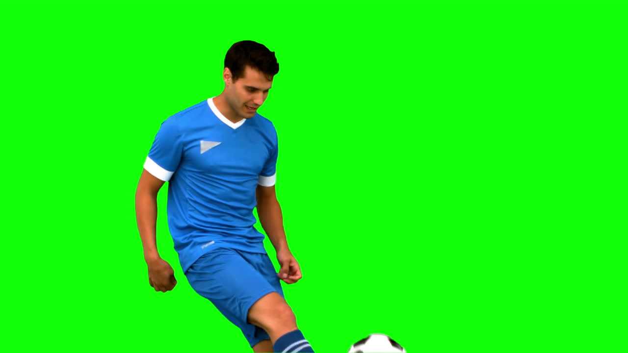 Attractive man juggling a football on green screen
