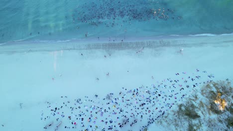 an aerial shot of a large group of people swimming in the ocean