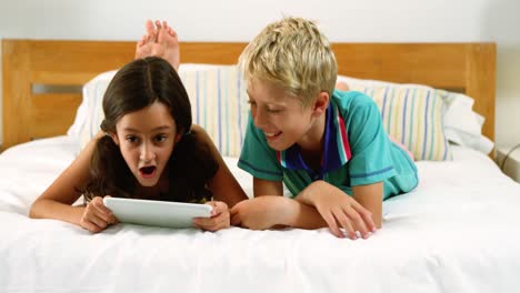 hermanos usando tableta digital en el dormitorio