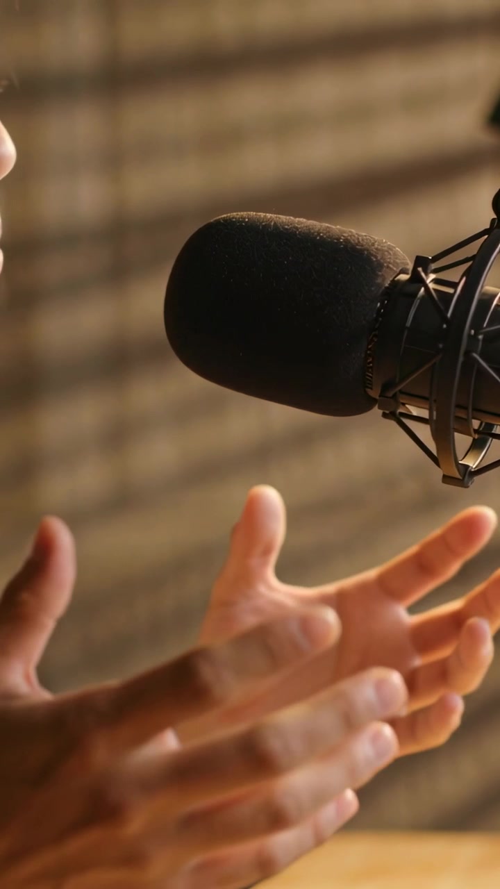 Video verticale: Presentatore che applaude con orologio, parla al microfono in studio, inizio del discorso per un podcast.