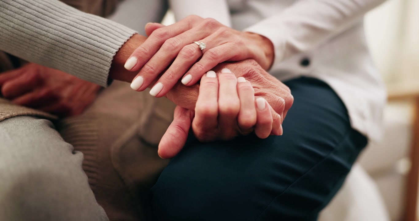 Primo piano di un caregiver che conforta una persona anziana tenendole la mano
