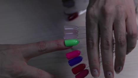 mujer eligiendo el color del esmalte de uñas para la manicura. selección del color de la laca de uñas. mujer eligiando el color de las uñas de tester.