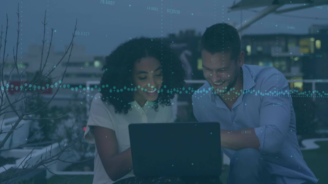 Woman typing on laptop on rooftop, man pointing at screen while animated business data emerging