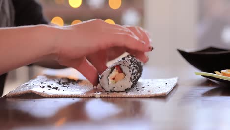 making sushi at home kitchen. woman hands rolling homemade sushi.