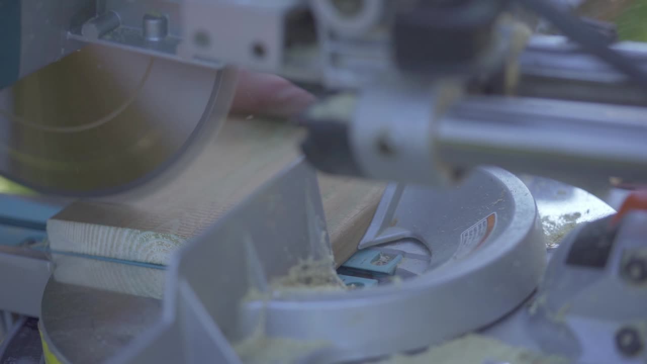 primer plano de la sierra de inglete cortando tablones de madera en el taller de bricolaje