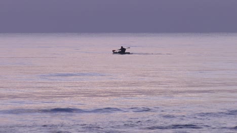 Sea-kayak-on-calm-sea-at-dawn,-man-paddling-canoe-at-sunrise,-mediterranean-coast