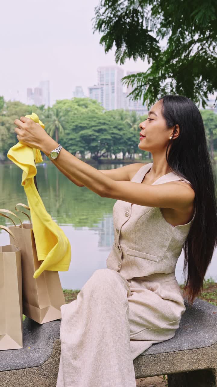 Woman looking at a yellow shirt by the lake in the park