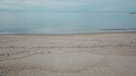 Desolate-white-sandy-beach-looking-out-at-horizon-with-small-waves