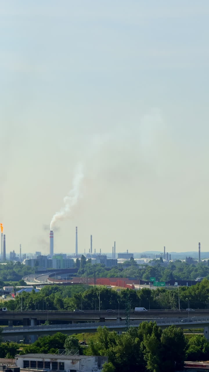 Smoke rises over industry. Factory smokestacks release emissions into the sky over a sprawling industrial area on a clear day