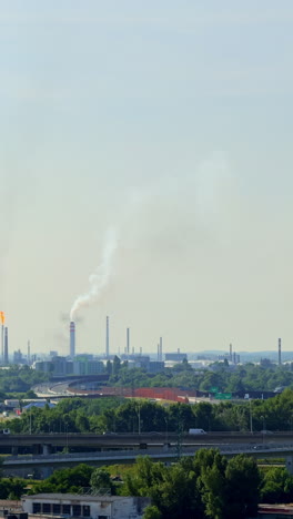 smoke rises over industry. factory smokestacks release emissions into the sky over a sprawling industrial area on a clear day