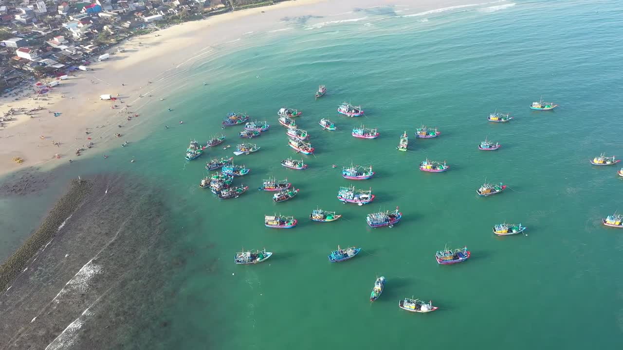 Aerial view of colorful fishing boats floating in turquoise waters of Nha Trang Bay, Vietnam. A vibrant seascape under bright daylight, highlighting coastal activity and serene sea