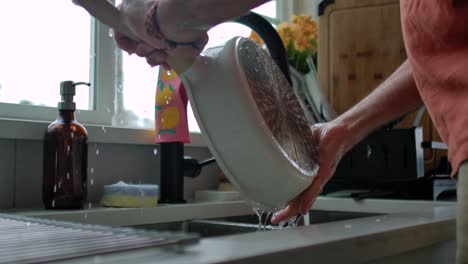 man washing dirty dishes at kitchen sink static slomo