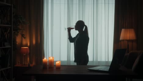woman drinking wine by the window at night