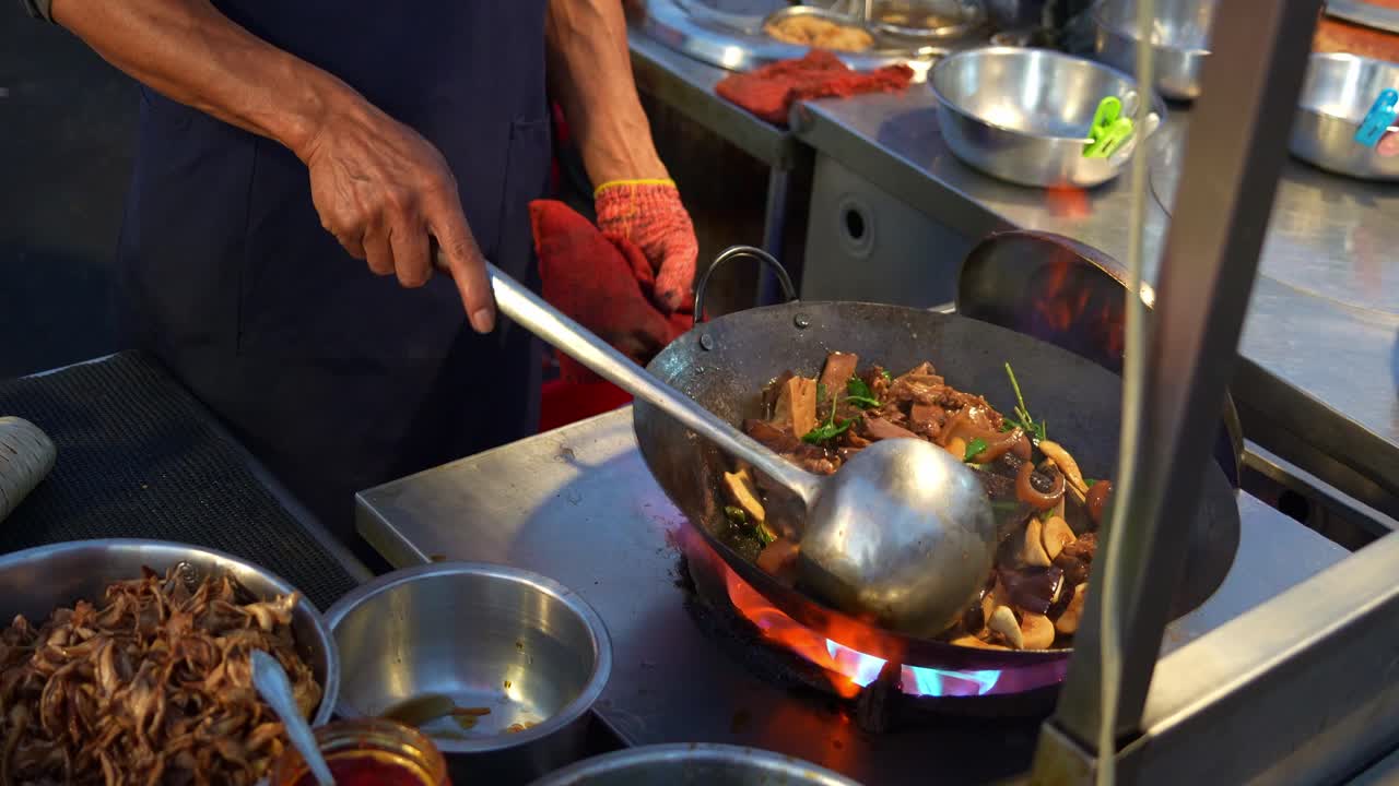 A street food vendor skillfully swirls the wok, tossing and mixing ingredients as delicious three-cup stir-fry sizzles over roaring flames, close up shot.