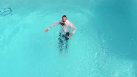 hombre de negocios vestido nadando en la piscina