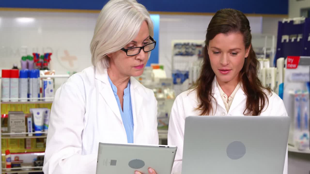 디지털 태블릿과 노트북을 사용하는 약사들