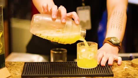 bartender pouring cocktail into a glass