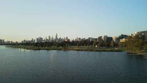 Aerial-drone-pan-of-a-lake-and-the-city-backdrop-in-Melbourne,-Victoria,-Australia