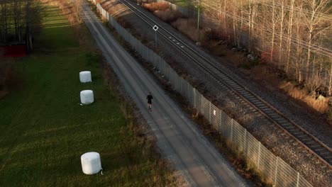 man running down countryside dirt road next to railroad near ostersund, sweden