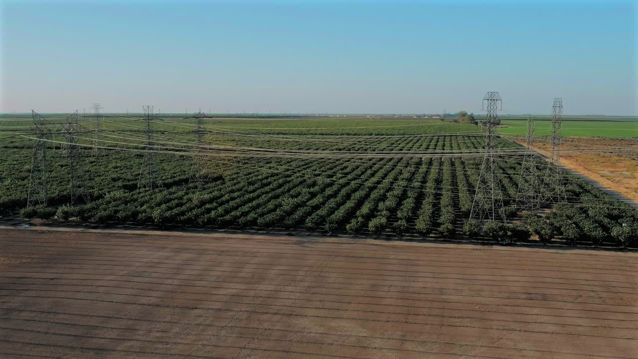 vista aérea de líneas eléctricas sobre campos rurales con plantas verdes en el valle central, california